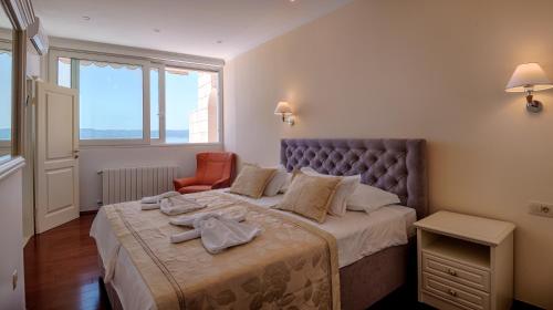 a bedroom with a large bed and a chair at Apartmani D&D Sosič in Brela