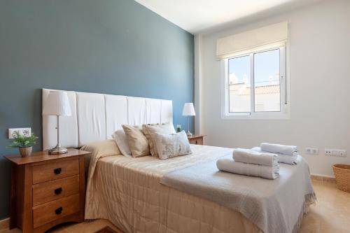 Un dormitorio blanco con una cama grande con toallas. en Casa Jaime, en Vejer de la Frontera