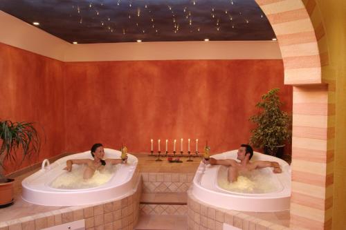 two men are sitting in tubs in a room at Hotel und Landgasthof Altwirt in Großhartpenning