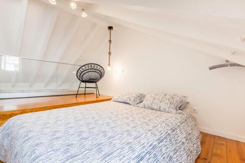 a bedroom with a bed and a chair in it at Stylish Getaway in a Mezzanine Flat by the Castle in Lisbon