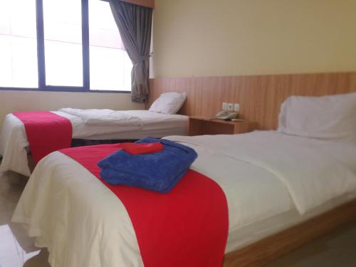 a hotel room with two beds with red and white at Hotel Mayang Sari 1 in Jambi