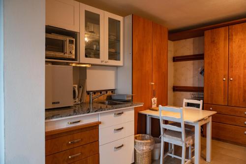 eine Küche mit weißen Schränken und einem Tisch mit einem Stuhl in der Unterkunft Landhaus ELisabeth in Obereching
