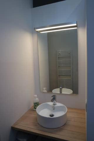 une salle de bain avec un lavabo et un miroir dans l'établissement Une Nuit au Soleil, à Bayeux