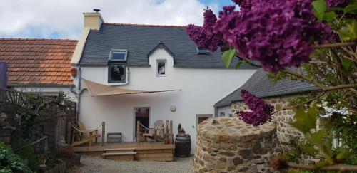 uma casa branca com um pátio e flores roxas em Île ô des capucins em Roscanvel