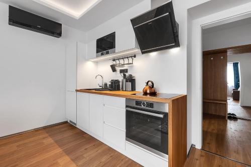 uma cozinha com armários brancos e um forno com placa de fogão em Nový designový apartmán s klimatizací em Rychnov nad Kněžnou