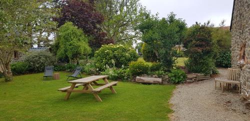 a wooden picnic table and benches in a garden at Île ô des capucins in Roscanvel