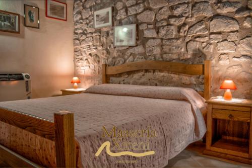 a bedroom with a bed with a stone wall at Masseria Xireni in Castellana Sicula