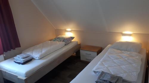 two beds in a small room with two lamps at Appartement Esta in Buren