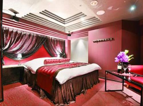 - une chambre avec un lit et un mur rouge dans l'établissement ホテル ジェムジェム 十三, à Osaka