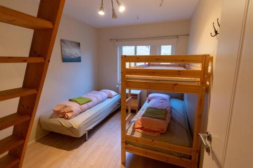 two bunk beds in a room with a ladder at Hvammur 2 Guesthouse Red House in Blönduós