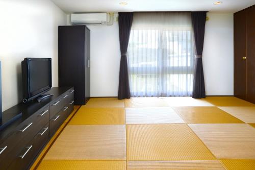 a living room with a tv and a window at wisteria Ocean Nakijin in Nakijin
