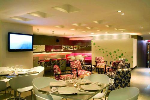 a restaurant with white tables and chairs and a television at San Simon Hotel Pereira in Pereira