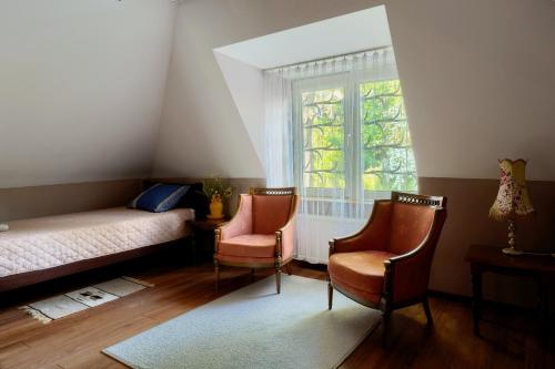 a bedroom with a bed and two chairs and a window at Dom z widokiem na Park in Nałęczów