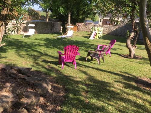 three chairs sitting in the grass in a yard at Gîte de la Grenouille in La Cambe