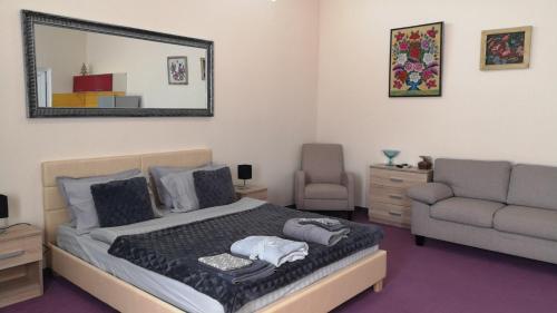 1 dormitorio con cama, sofá y espejo en Заміський будинок Fresh air, en Vinyntsi