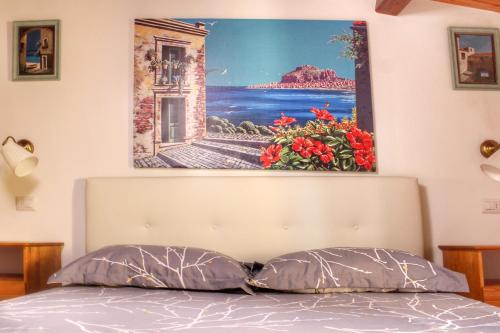 obraz na ścianie nad łóżkiem z dwoma poduszkami w obiekcie Gerani House w Cefalù