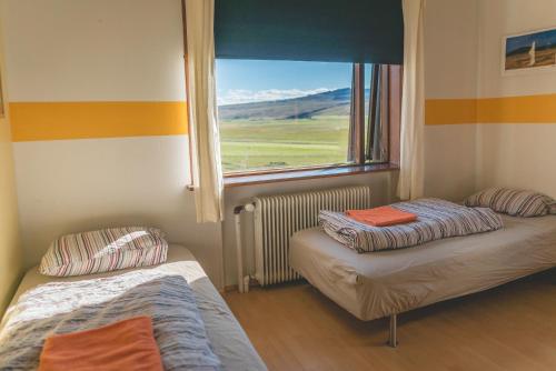 two beds in a room with a window at Hvammur 2 Guesthouse in Blönduós