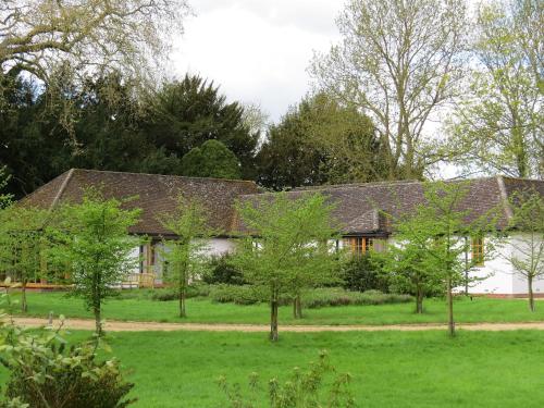 uma casa com árvores em frente em The Lodge at Hemingford Grey House em Hemingford Grey