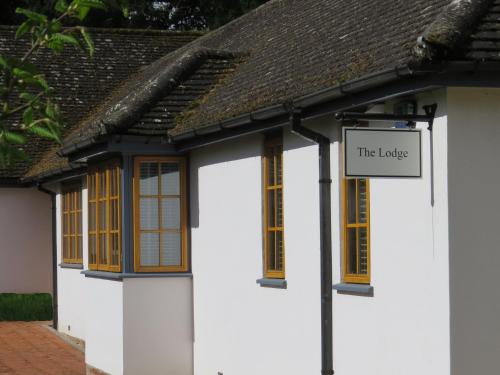 Ein weißes Gebäude mit einem Schild, das diese Lodge liest. in der Unterkunft The Lodge at Hemingford Grey House in Hemingford Grey