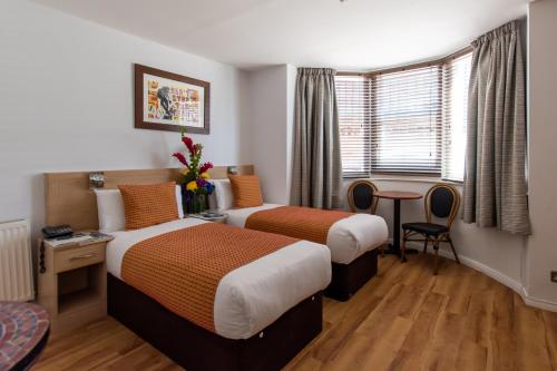 a hotel room with two beds and a table at New Steine Hotel - B&B in Brighton & Hove