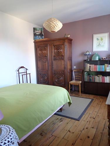 - une chambre avec un lit vert et une armoire en bois dans l'établissement La Roche Pérégrine, à Châtel-Guyon
