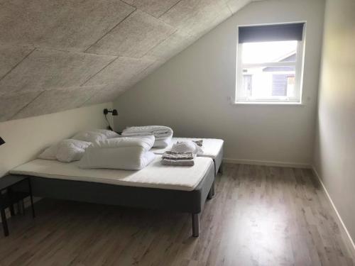a white bedroom with a bed with a window at Lokk-Inn Apartments in Norðdepil