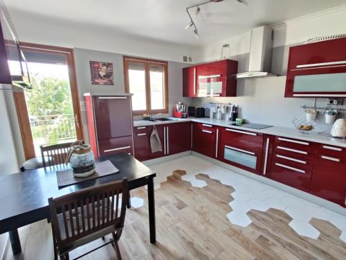 uma cozinha com armários vermelhos, uma mesa e cadeiras em Maison 190m2 - Entre Paris et Disneyland em Gagny