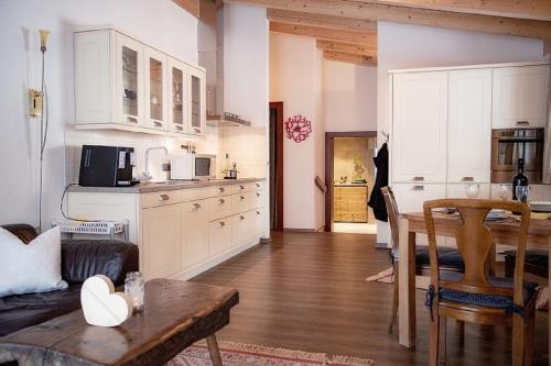 eine Küche mit weißen Schränken und einem Tisch im Zimmer in der Unterkunft Ferienwohnung Birkentalblick in Nesselwängle