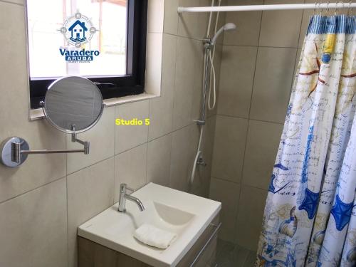 a bathroom with a sink and a shower curtain at Varadero Marina Airport Guests Rooms in Oranjestad