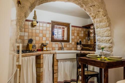 a kitchen with a sink and a counter with a table at Trulli Sabrina Resort in Locorotondo