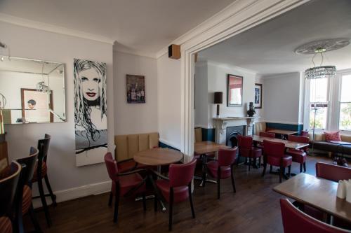 a dining room with tables and red chairs at New Steine Hotel - B&B in Brighton & Hove