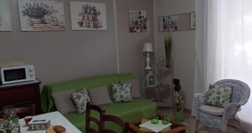 uma sala de estar com um sofá verde e uma mesa em Bilocale centrale con veranda a pochi metri dalla spiaggia em Castelsardo