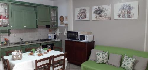 una cucina con armadi verdi, tavolo e forno a microonde di Bilocale centrale con veranda a pochi metri dalla spiaggia a Castelsardo