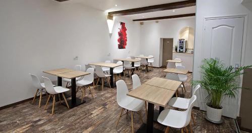 Habitación con mesas de madera y sillas blancas. en Hôtel Le Chambellan, en Dijon