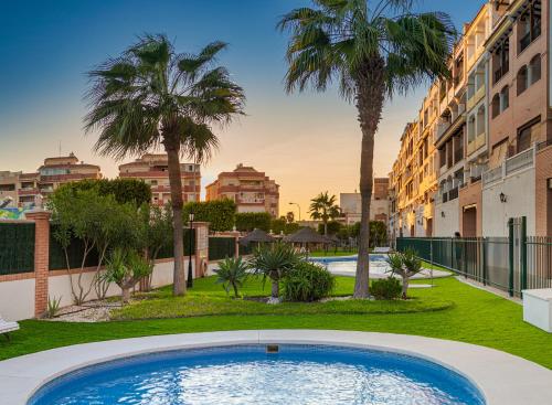 una piscina con palmeras y edificios en Apartamento 2 dormitorios en la mejor zona de Roquetas, en Roquetas de Mar