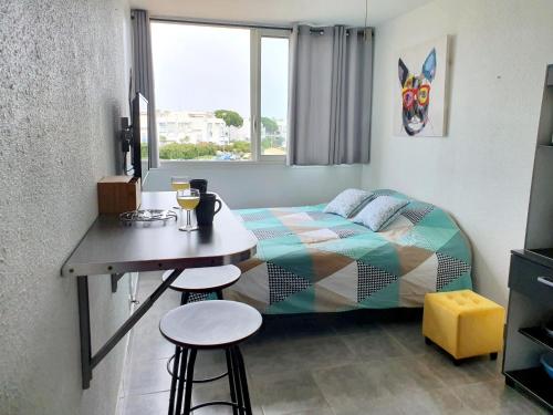 a bedroom with a bed and a table with stools at le studio du palais de la mer in Le Grau-du-Roi