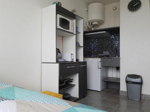 une petite cuisine avec un évier et un micro-ondes dans l'établissement le studio du palais de la mer, au Grau-du-Roi