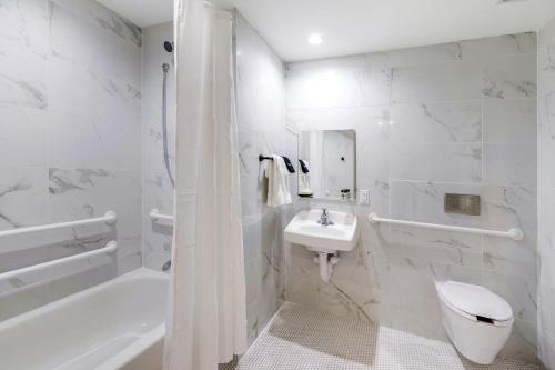a bathroom with a tub, toilet and sink at Ocean Treasure Beachside Suites in Fort Lauderdale