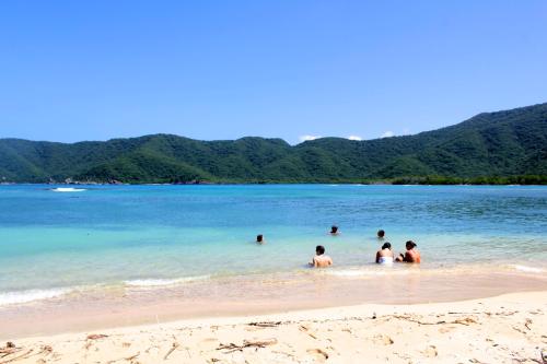 a group of people in the water at a beach at Hotel Boutique Casa Carolina in Santa Marta