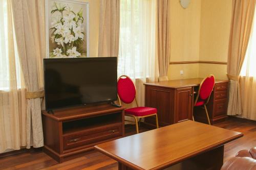 a living room with a flat screen tv and red chairs at Korona Hotel in Boryspilʼ