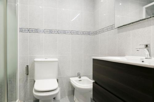 a white bathroom with a toilet and a sink at Apartamento Málaga Velázquez in Málaga