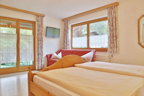 a bedroom with two beds and a chair and windows at Haus Adlerkanzel in Scharnitz