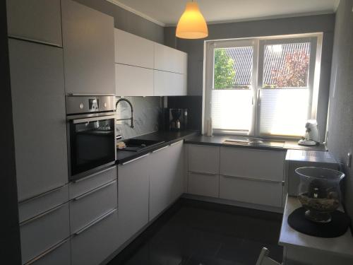 a kitchen with white cabinets and a stove top oven at Feriendomizil im Musikerviertel in Otterndorf in Otterndorf