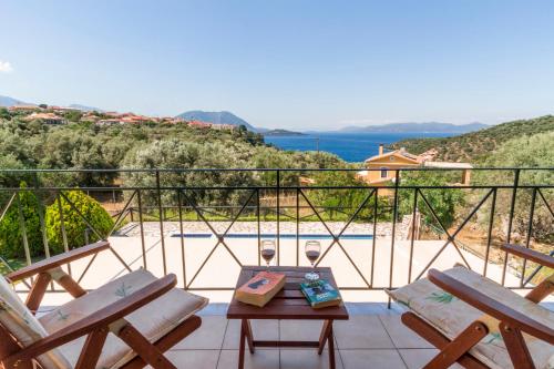 a balcony with two chairs and a table and a pool at Villa Aphrodite in Meganisi