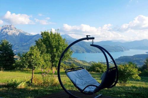 a swing seat with a view of a lake and mountains at Belle maison Vue imprenable lac de Serre-Ponçon in Prunières
