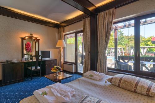 スナゴヴにあるHotel Snagov Clubのベッドと大きな窓が備わるホテルルームです。