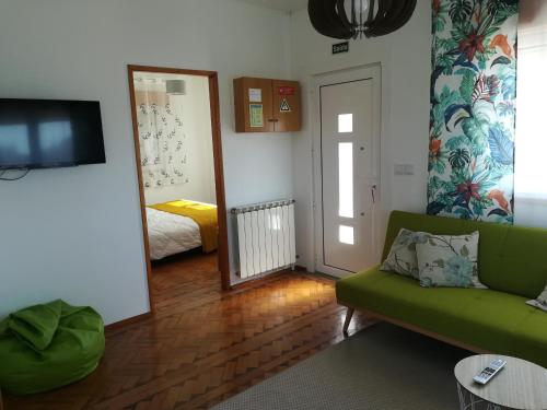 a living room with a green couch and a mirror at O Nosso Cantinho in Louriçal