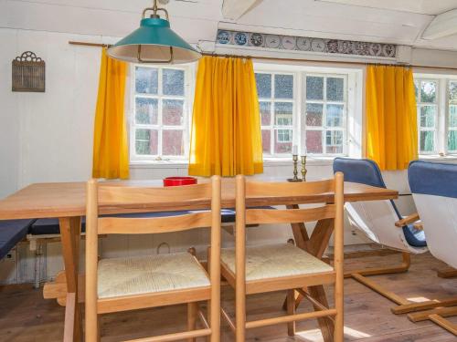 een eetkamer met een houten tafel en gele gordijnen bij 4 person holiday home in Fan in Fanø
