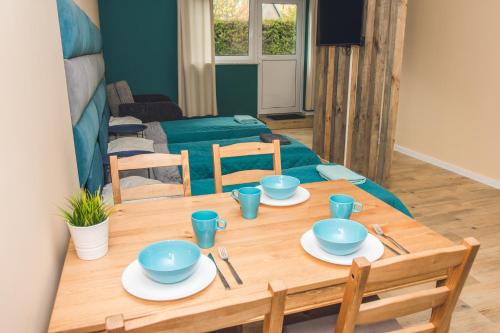a wooden table with blue bowls and plates on it at Apartamenty w Świeciu CS17 in Świecie