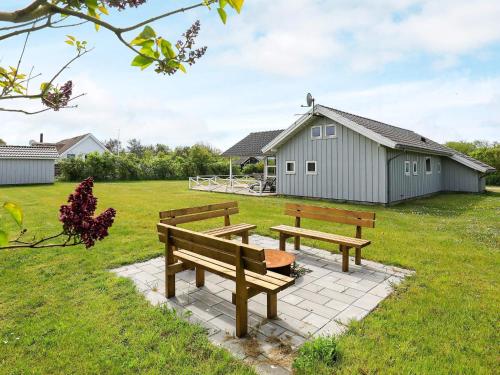 two wooden benches sitting in a field with a building at 8 person holiday home in Lemvig in Lemvig